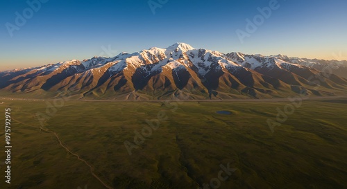 Aerial view of snow-capped mountain range and lush green valley at sunset