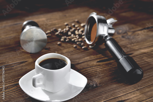 Fotografía a cup of coffee, coffee beans, a coffee horn and a tamper on a wooden background