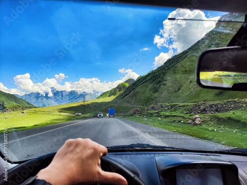 Scenic drive on mountain road with green hills and blue sky