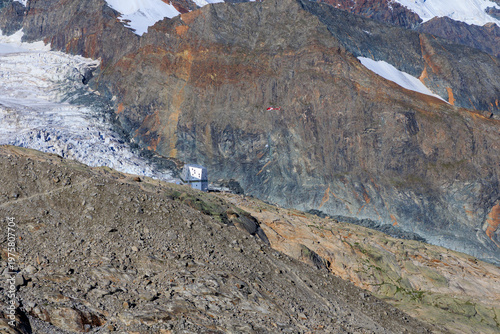 Helicopter delivering supplies to mountain hut Monte Rosa Hut at Monte Rosa massif with mountain glacier panorama in Pennine Alps, Switzerland