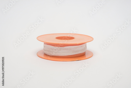Foto White PTFE thread seal tape on an orange plastic spool isolated on a white background