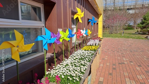 colorful pinwheels and flower garden decoration along building walkway in sunny day