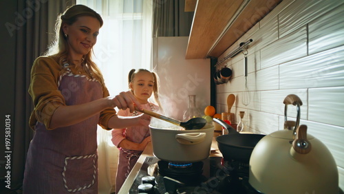 Friendly family cooking soup at kitchen closeup. Loving mother teaching daughter