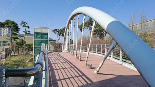 modern pedestrian bridge with curved steel structure in urban park
