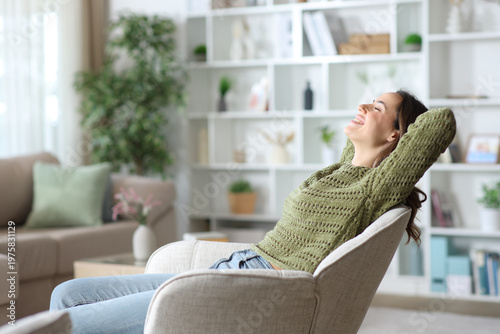 Happy woman relaxing sitting on armchair in the living room