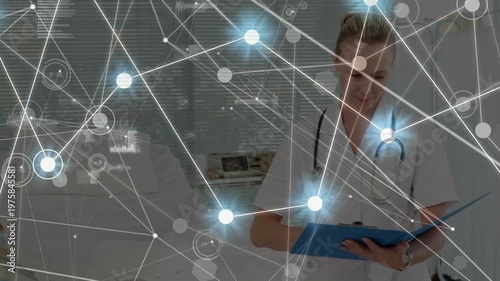 A doctor is writing on a clipboard and looking at the camera