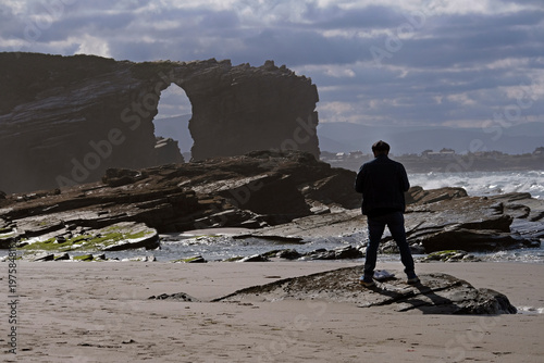 Man seen from the back, standing at the coast of Galicia, Spain, on a day with dramatic sky