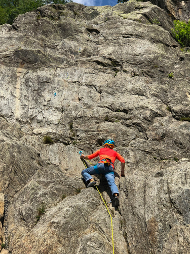 A woman climber ascending a steep alpine rock face in Les Gaillands, Chamonix, displaying focus, strength and determination during an extreme outdoor adventure in the french alps - stock photo