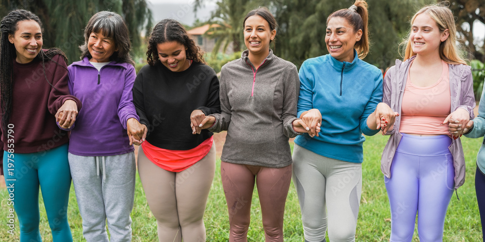 Fototapeta premium Women holding their hands during meditation class with people of different age and body types - Healthy lifestyle and female circle connection concept - Main focus on center latin female face