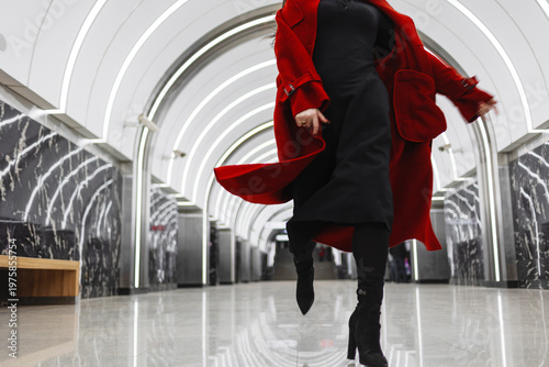 A dark-haired woman in a crimson coat on a metro platform, rushing for business