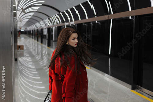A stylish brunette in a red coat rushing on a subway platform, city life