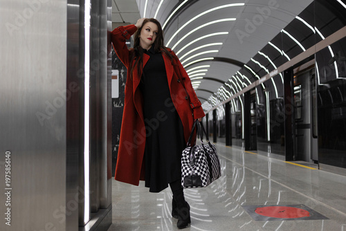 A dark-haired woman in a crimson coat on a metro platform, rushing for business