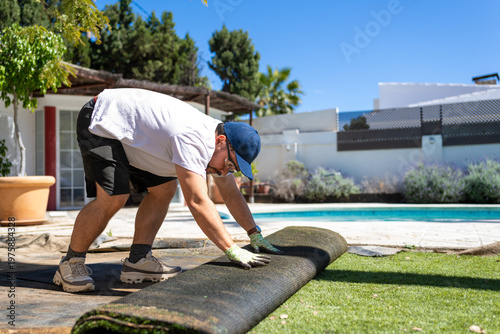 Foto Middle aged man removing artificial grass in a sunny backyard with a swimming po