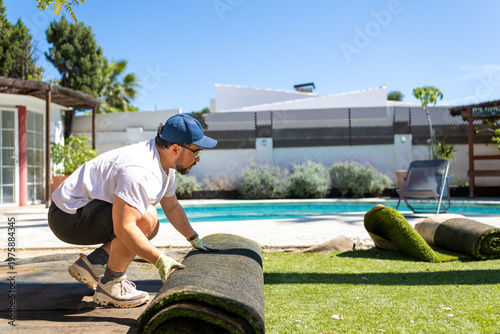Outdoor home improvement with man removing synthetic grass near pool