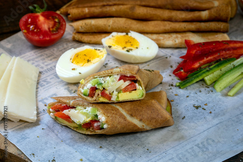 Tortilla with cucumbers, avocado, cheese, tomatoes, and hard-boiled eggs.