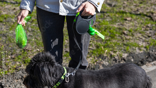 Fotografie Woman with poop bag dispenser outdoors, responsible pet care, hygiene practice, urban service, cleanliness