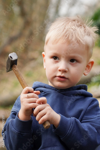 Little boy holding small garden tool, child learning practical skills outdoors, helping in garden and exploring nature