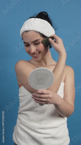 Beautiful woman using jade gua sha scraper tool for facial massage