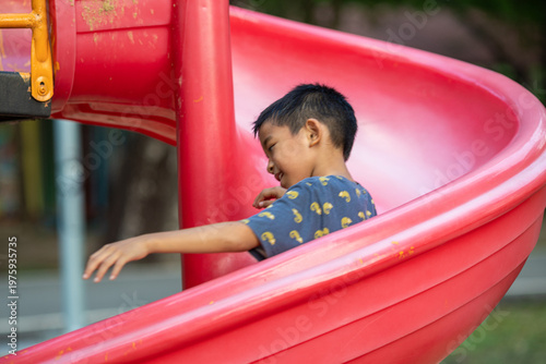 Little school boy enjoy slider outdoor playground park
