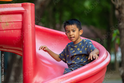Little school boy enjoy slider outdoor playground park