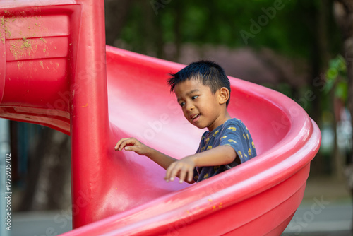 Little school boy enjoy slider outdoor playground park
