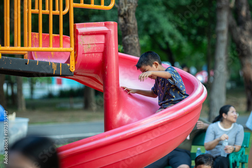 Little school boy enjoy slider outdoor playground park