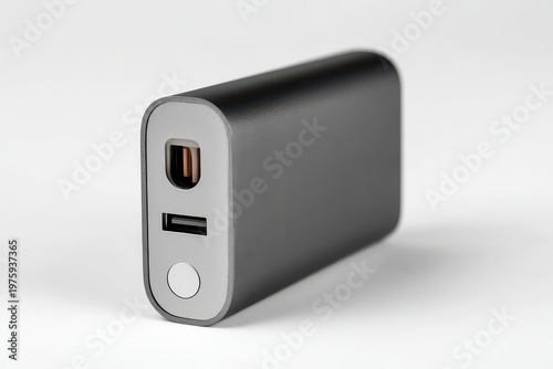 Black portable power bank with USB ports and indicator light against a clean white background with subtle studio lighting highlighting its metallic texture and compact design