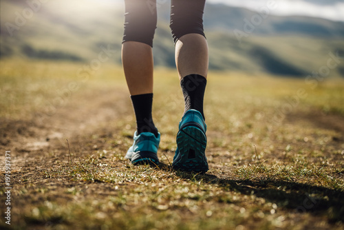 Fitness woman legs walking on high altitude grassland mountain trail