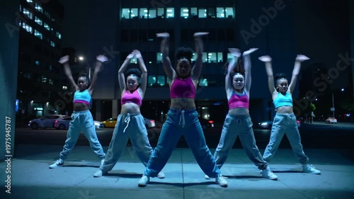 Starting on beat, five dancers performing hip moves on sidewalk, shifting, ending squat, crop tops