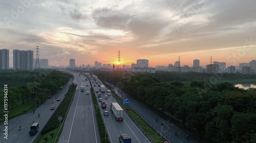 Aerial sunrise view of Phap Van Cau Gie expressway and Ring Road 3 in Hanoi with steady traffic, urban skyline, and soft morning haze