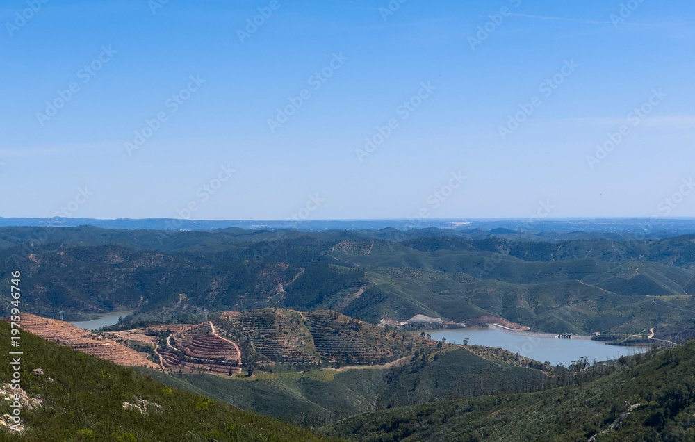 Fototapeta premium Lake with trees and a hill formation on the horizon.