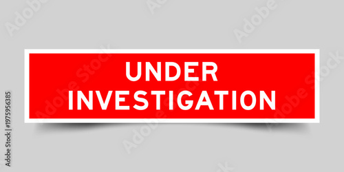 Red color square shape sticker label with word under investigation on gray background