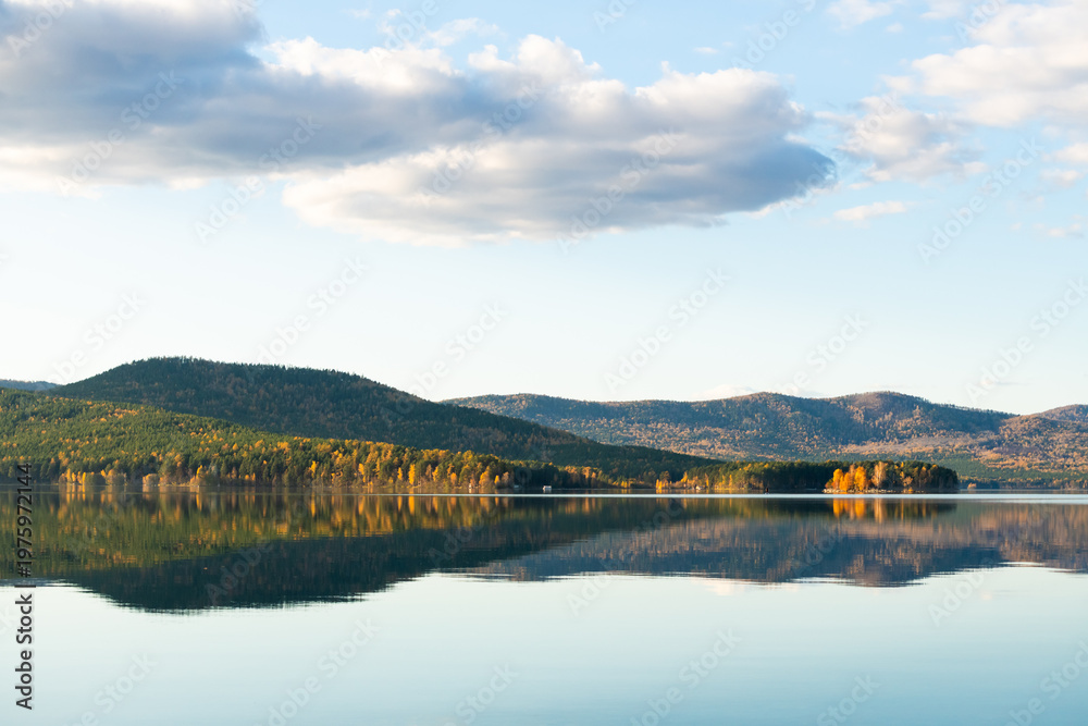 Fototapeta premium Beautiful lake at sunset. Mountains, trees and sky are reflected in the calm water surface.