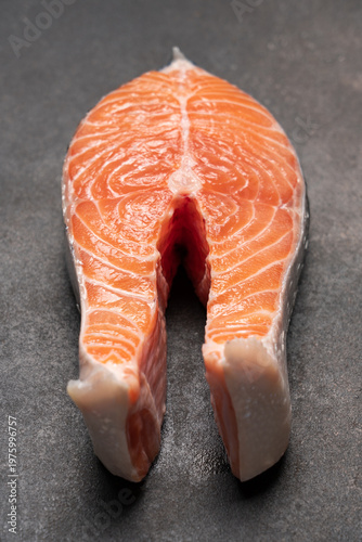 Macro top view of fresh salmon steak on dark brown background, raw fish texture, gourmet seafood concept