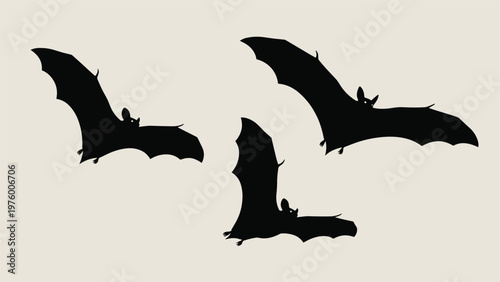 Silhouette of three bats flying in different positions against a neutral background, capturing a spooky or nocturnal atmosphere.