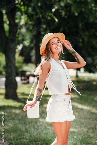 Εκτύπωση καμβά Young woman in straw hat white sleeveless top and light shorts enjoying sunny da