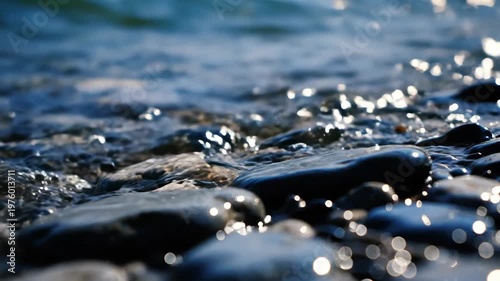 Moving stones along a calm shoreline with gentle waves and sunlit reflections