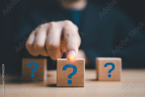 Question mark decision concept with hand select wooden block, symbolizing uncertainty, problem solving, critical thinking and choosing the right answer in business strategy and decision making process