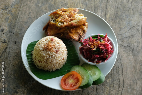 ayam geprek sambal kecombrang, kampong fried chicken with torch ginger chili sauce and sliced tomato and cucumber. Indonesian food.
