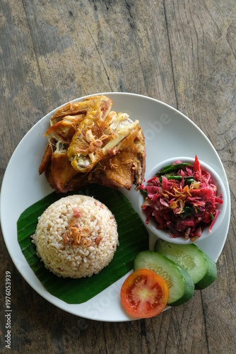 ayam geprek sambal kecombrang, kampong fried chicken with torch ginger chili sauce and sliced tomato and cucumber. Indonesian food.