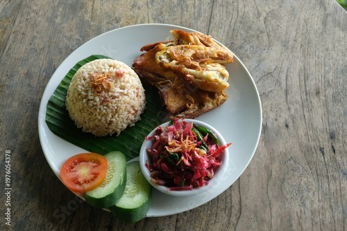 ayam geprek sambal kecombrang, kampong fried chicken with torch ginger chili sauce and sliced tomato and cucumber. Indonesian food.