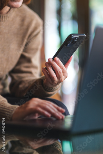 Vertical closeup image of a woman using smart phone and laptop computer