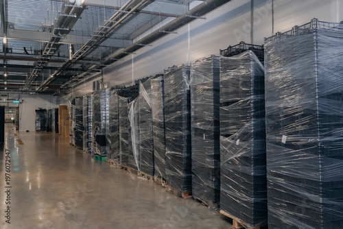 Obraz na płótnie Neatly stacked rows of dark plastic crates, securely wrapped in clear film, stan