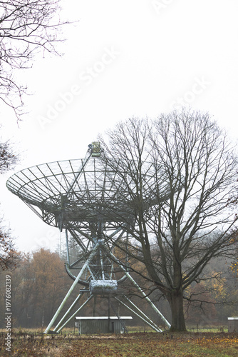 A striking technical shot of a massive white parabolic antenna belonging to the Westerbork Synthesis Radio Telescope (WSRT) array. Located on the historic grounds of the former Westerbork transit camp