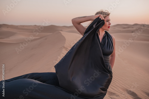 Close up portrait of elegant blond woman in black dress in desert, UAE. 