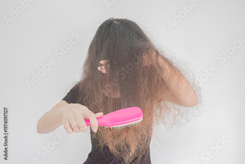A young woman with curly hair is combing her hair.