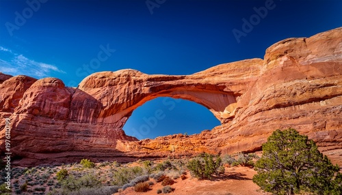 stunning red sandstone natural bridge framed by clear blue sky in arches park utah use travel blog hero image outdoor adventure brochure