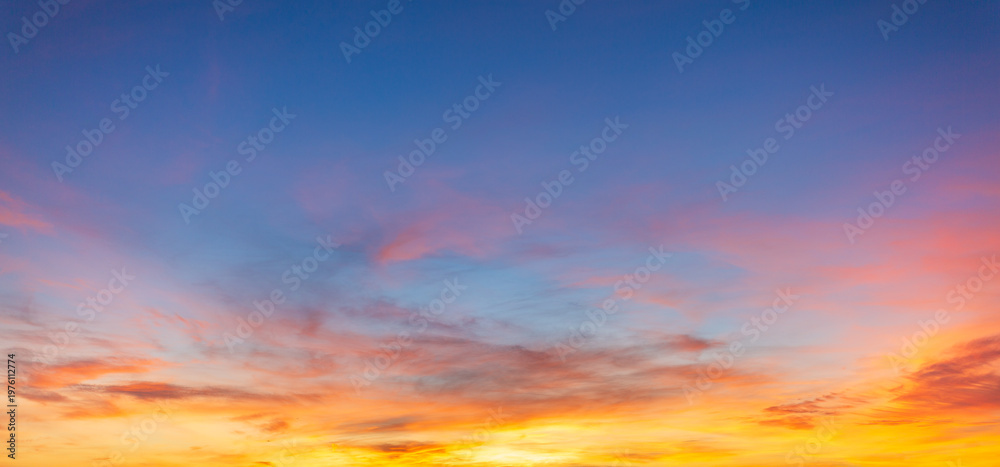 Fototapeta premium The skies at sunrise and sunset are breathtakingly beautiful, filled with colorful clouds and soft, gradual shades of blue,A breathtaking panoramic view of the evening sky during sunset, featuring.