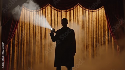 Man with flashlight on a stage.