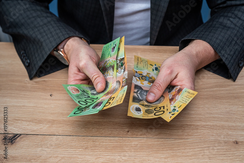 Businessman Hands Counting Fifty and One Hundred Australian Dollar Banknotes on Wooden Table